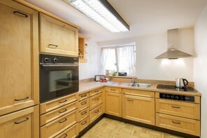 Eine Küche mit Holzausstattung, integriertem Backofen, Spüle und Herd.