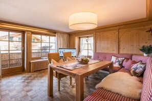 Ein Holzinterieur mit einem Esstisch, Stühlen, einer Couch und einem großen Fenster.