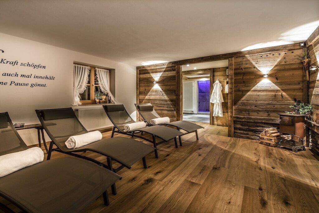 A spa room with wooden walls, a large mirror, and several lounge chairs.