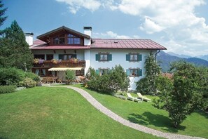 Un immeuble de deux étages doté d’un balcon, d’une allée pavée et d’une pelouse bien entretenue.