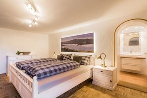 Une chambre à coucher avec un lit, une table de chevet, une lampe et un tableau au mur.