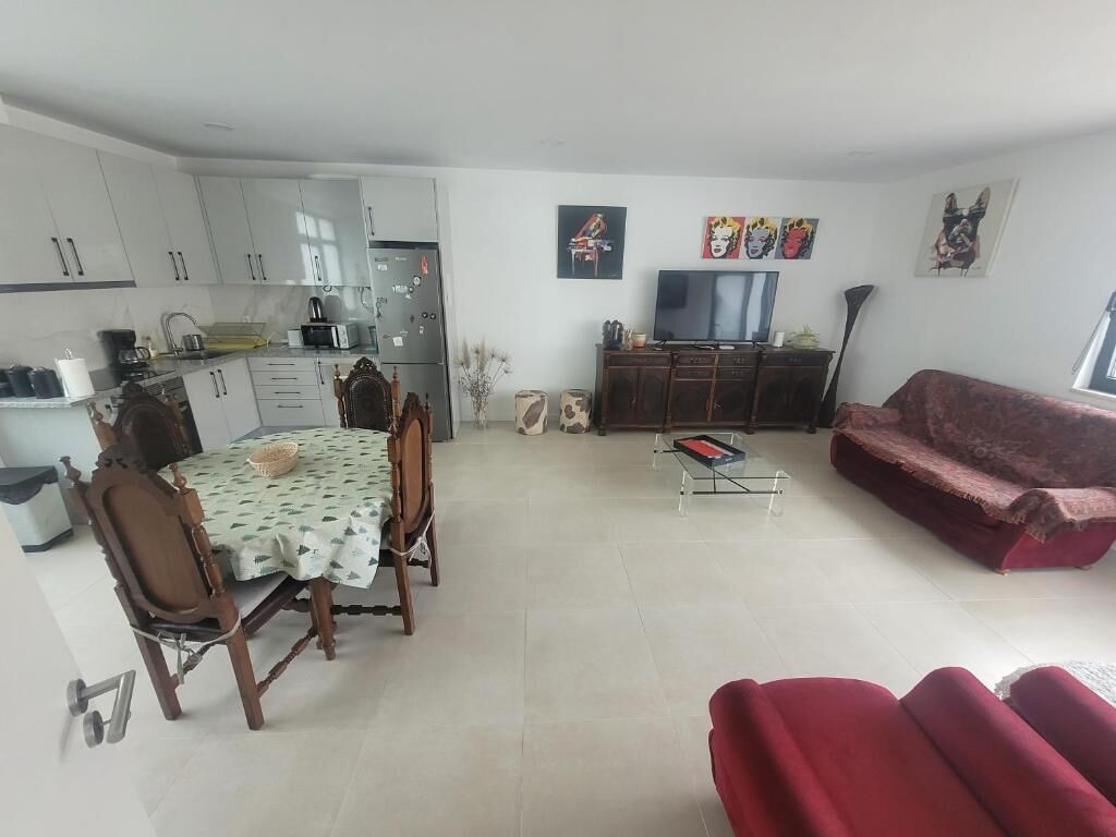 A compact living space with a dining area, a sofa, and a television.