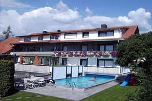 Ein zweistöckiges Gebäude mit Swimmingpool, Sitzgelegenheiten im Freien und einer Rutsche.