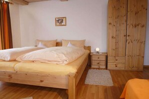 Ein Schlafzimmer mit einem hölzernen Bett, einem Nachttisch, einem Kleiderschrank und einem Teppich.