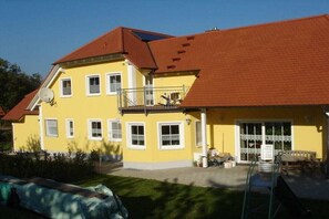 A yellow building with a red roof, multiple windows, and a balcony. - House by the Cherry Orchard (Leutenbach)