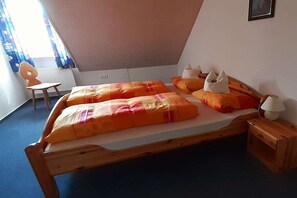 Een kamer met een houten bed, een klein tafeltje, een stoel en een lamp.