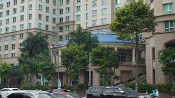A multi-story building with a central atrium, surrounded by parked cars and trees.