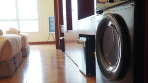 A laundry room with a washing machine, a drying rack, and a small table with a chair. - The Manor 2 (Thanh My Tay)