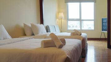 A hotel room with two beds, a window, a lamp, and a view of the city.