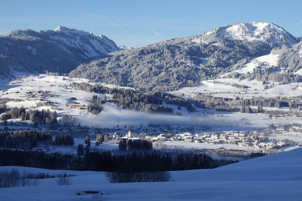 Ett snötäckt bergigt landskap med en stad som ligger inbäddad i dalen.