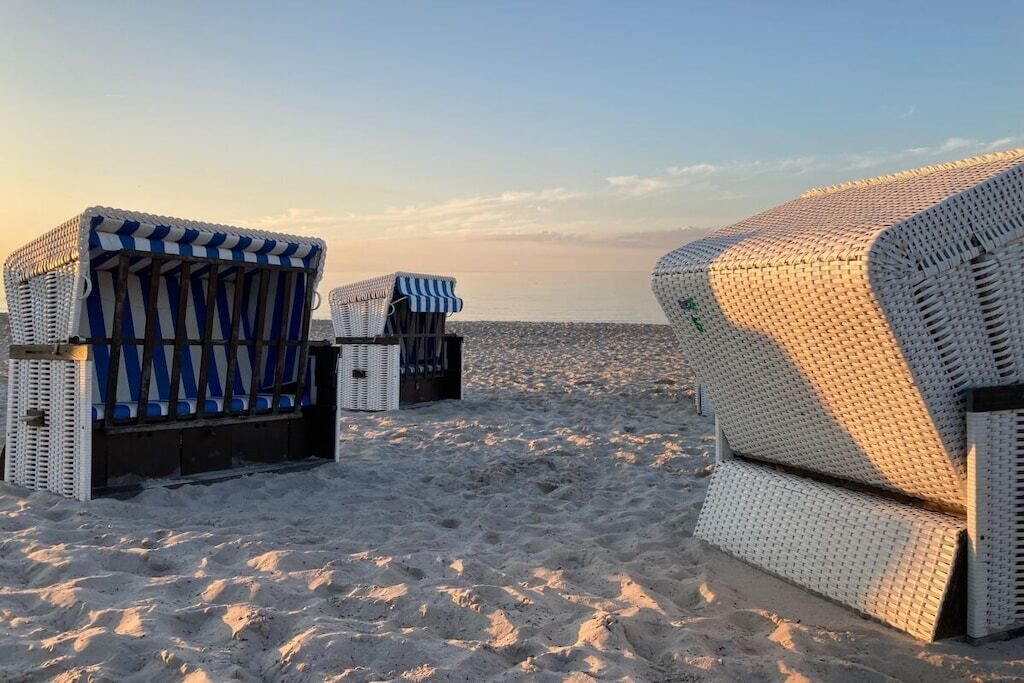Strandstühle und ein großes, weißes Gebäude am Sandstrand.