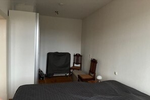 Ein Schlafzimmer mit einem Bett, einem Sessel, einem kleinen Tisch und einem Kleiderschrank.