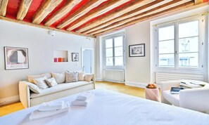 Una habitación de hotel con una cama, un sofá, una mesita y una ventana.