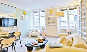 Una sala de estar moderna con un sofá, sillones, una mesa de centro, un televisor y una estantería.