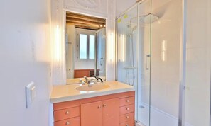 Un baño con un espejo grande, un lavabo, una ducha y un armario.