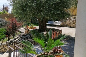Ein Garten mit einer Steinmauer, einem Baum und einer Bank.