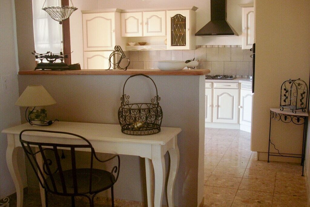 A kitchen with white cabinetry, a stove, and a dining area with a table and chair.