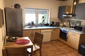 Eine kompakte Küche mit Kühlschrank, Backofen, Mikrowelle und einem Essbereich mit Tisch und Stühlen.
