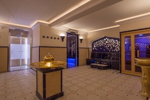 Un hall con mostrador de recepción, una fuente decorativa y una zona de estar con un papel tapiz estampado.