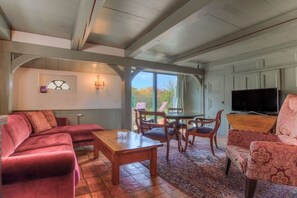 A cozy living room with a sofa, a coffee table, and a TV. There is a dining area with chairs and a table. The room has a large window and a view of the outdoors. - Friesenhaus Sara (S4) (Wenningstedt)
