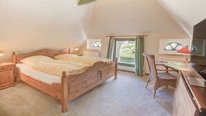 Quarto com cama de madeira, escrivaninha, cadeira e janela com cortinas.