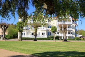 A multi-story hotel with balconies, surrounded by a well-maintained lawn and trees. - Villa Parkblick Apt. 27 (Kühlungsborn Ost)