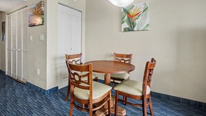 Ein Hotelzimmer mit einem runden Holztisch, vier Stühlen, einer Deckenleuchte, einer Tür und einem Wandbild.