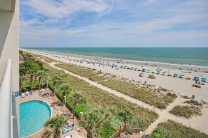 A beach view with a pool, umbrellas, and lounge chairs. - Oceanfront 1BR Suite + Lazy River & Hot Tub (Myrtle Beach)