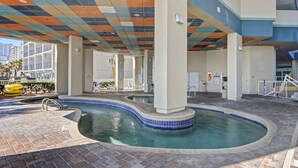 Ein Poolbereich mit gefliestem Boden, einem geschwungenen Pool und einer farbenfrohen Decke.