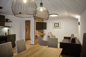 A modern interior with a dining area, seating, a television, and a kitchen. - Modern Suite With Conservatory (Gaschurn)