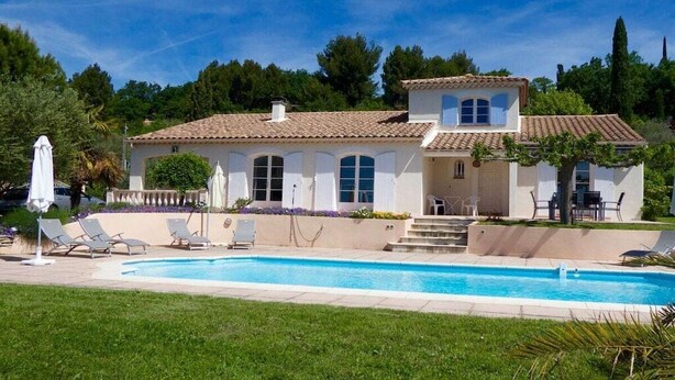 A two-story house with a swimming pool, a covered patio, and a garden.