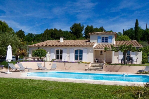 Une maison à deux étages avec une piscine, un patio couvert et un jardin.