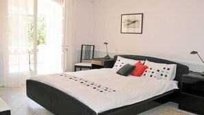 A bedroom with a bed, bedside tables, a chair, a lamp, and a framed picture on the wall.