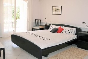 Une chambre à coucher avec un lit, des tables de chevet, une chaise, une lampe et un tableau encadré au mur.