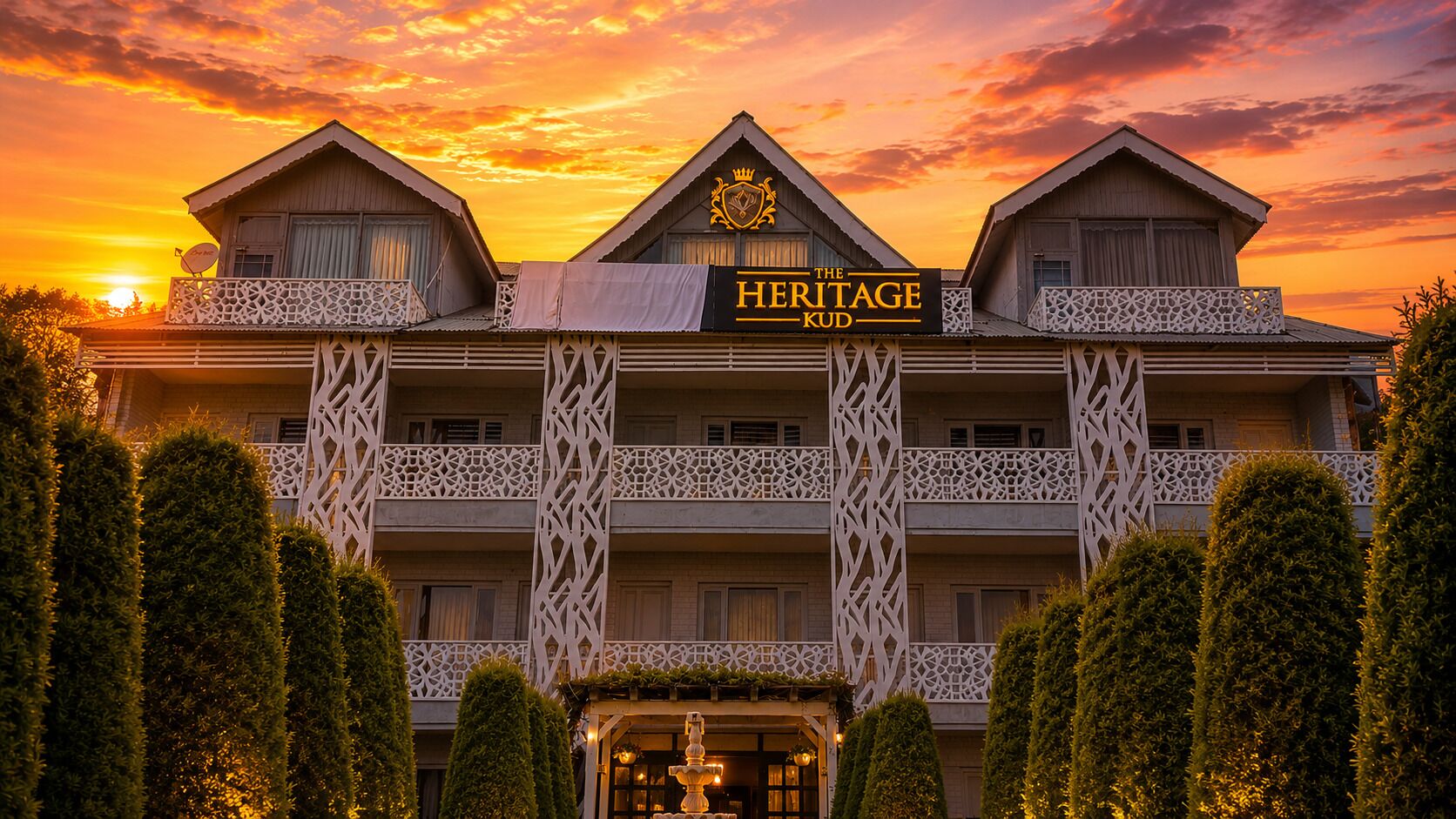 A hotel with a sign reading 'The Heritage Kud' and a traditional architectural style with balconies and decorative lattice work.