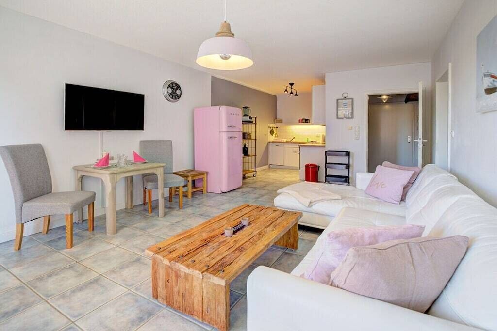 Una sala de estar moderna con un sofá blanco, una mesa de centro de madera y una televisión.