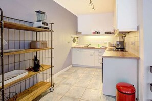 A compact kitchen with a dishwasher, a coffee maker, and a red trash bin. - Holiday apartment with 1 bedroom (St. Peter-Ording)