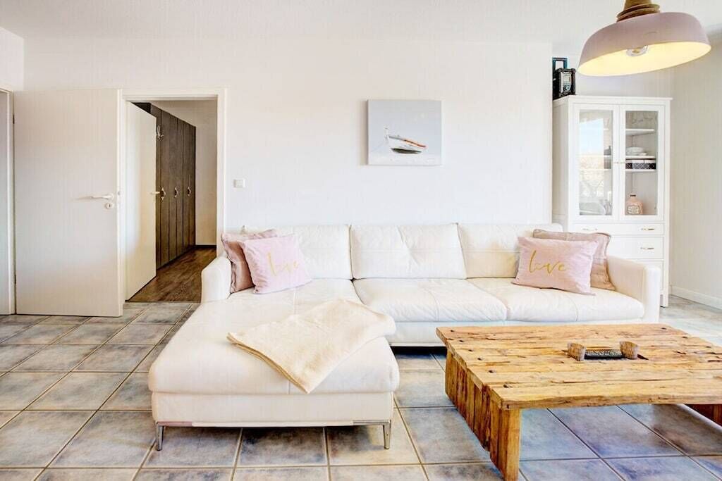 Un salon avec un canapé blanc, une table basse en bois et un meuble.