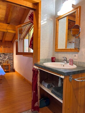 Een houten interieur met een badkamer, inclusief een wastafel, spiegel en handdoekrek.
