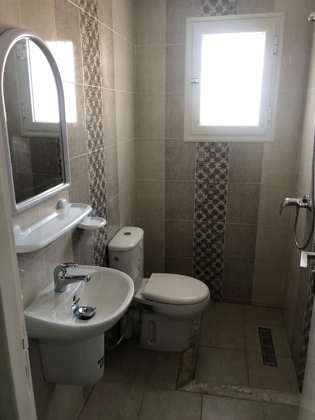 A compact bathroom with a toilet, sink, and a window.
