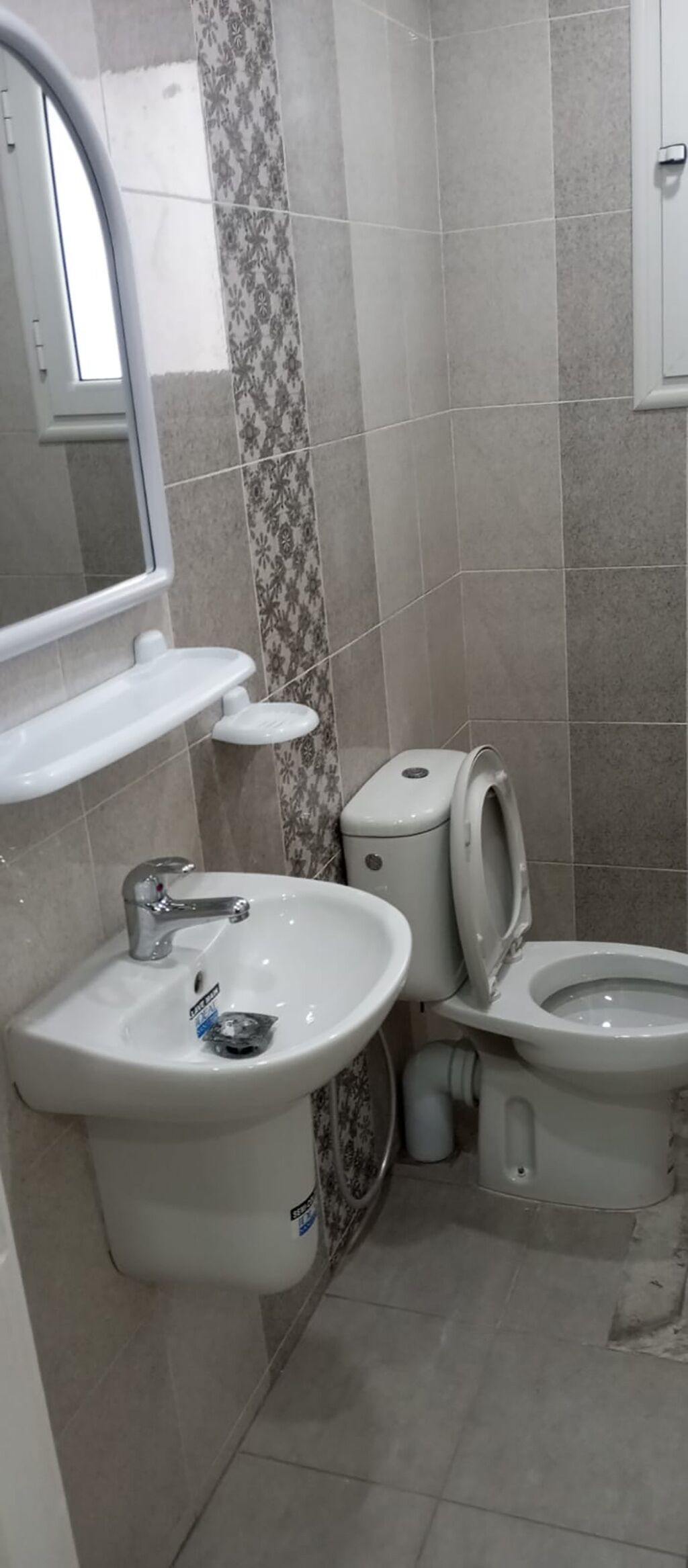 Un baño con lavamanos blanco, inodoro y espejo.