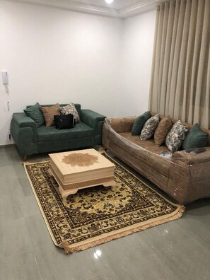 Una sala de estar con dos sofás, una mesa de centro y una alfombra estampada.