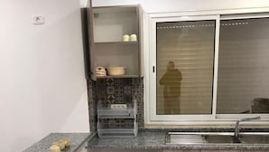 Ett kök med en bänkskiva i granit, en inbyggd ugn, ett fönster med persienner och träskåp.