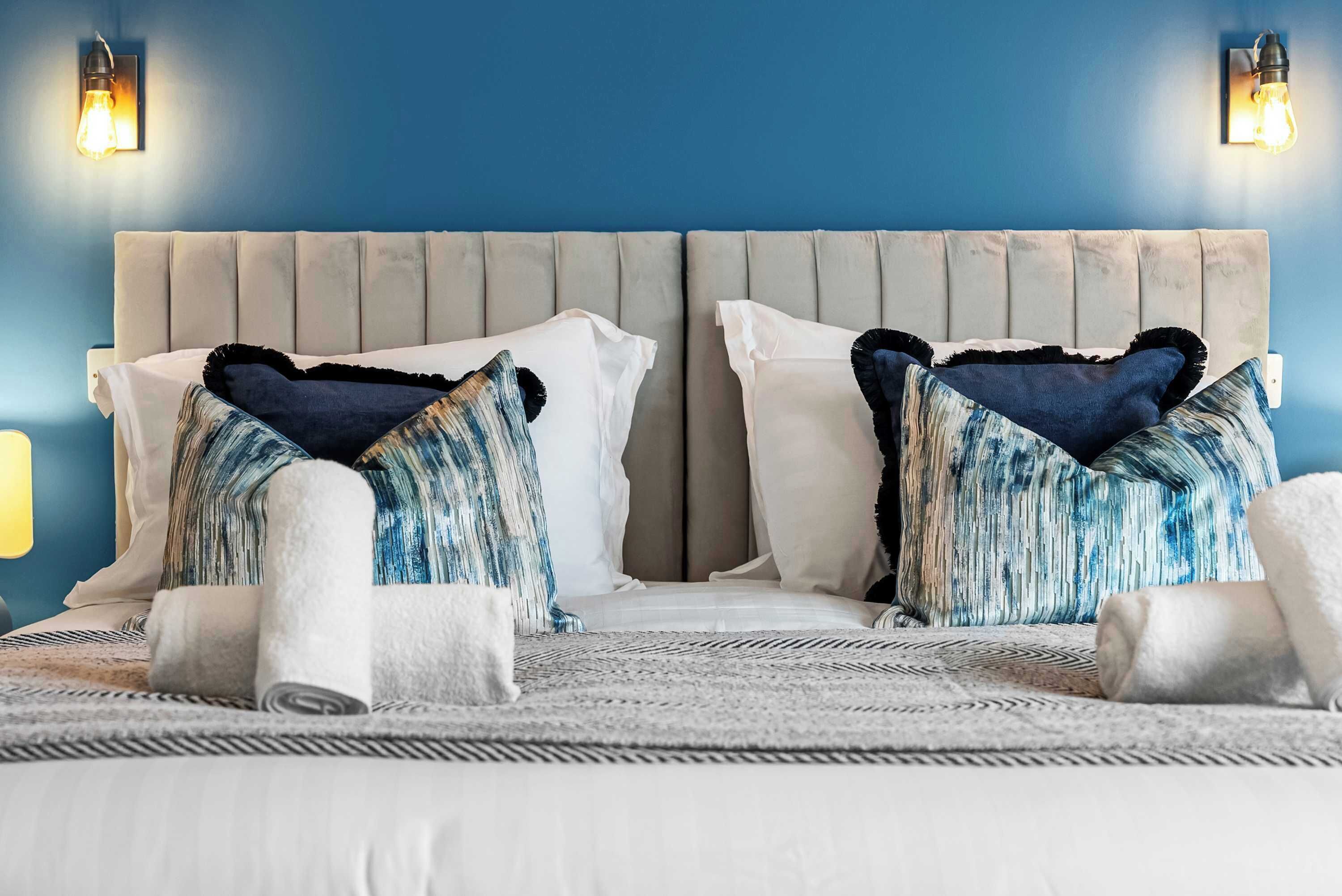Ein Bett mit zwei Kissen, einem Kopfteil und einer Wandleuchte.
