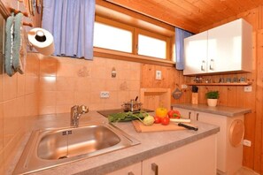 Eine Küche mit Spüle aus Edelstahl, Holzschränken und einer Arbeitsplatte mit frischem Gemüse.