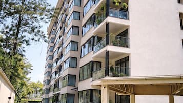 A multi-story residential building with balconies, a covered entrance, and a paved driveway.