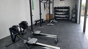 A gym with weightlifting equipment, a pull-up bar, and a bench.