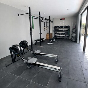 Academia com equipamentos de musculação, barra de exercícios e um banco.
