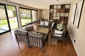 Uma sala de estar espaçosa com sofá, mesa de centro e uma janela grande com vista para o exterior.