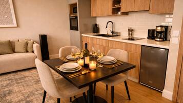 A dining area with a table set for four, a sofa, and a kitchen in the background.